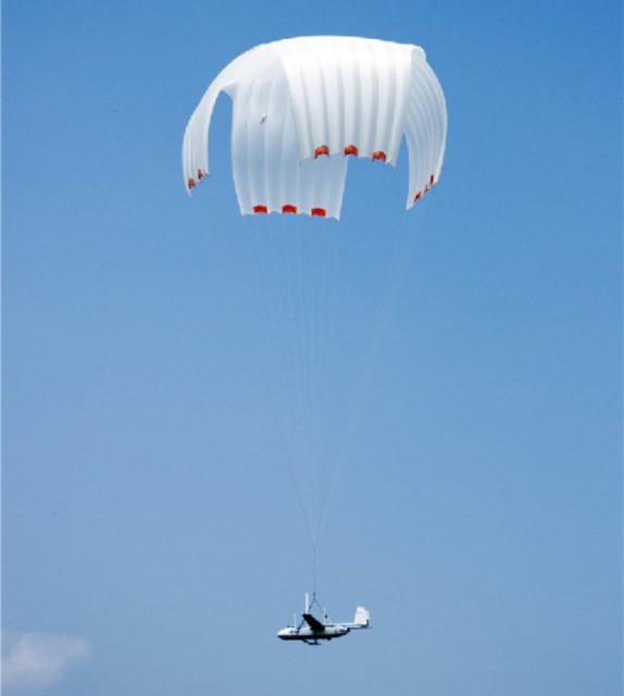 An unmanned aerial vehicle carrying communication relay system descends through the sky and prepares to land onto the designated position.